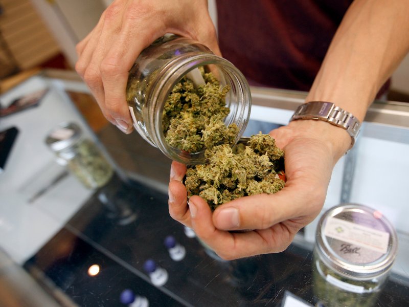 &copy; David McNew/Getty, A budtender pours marijuana from a jar.