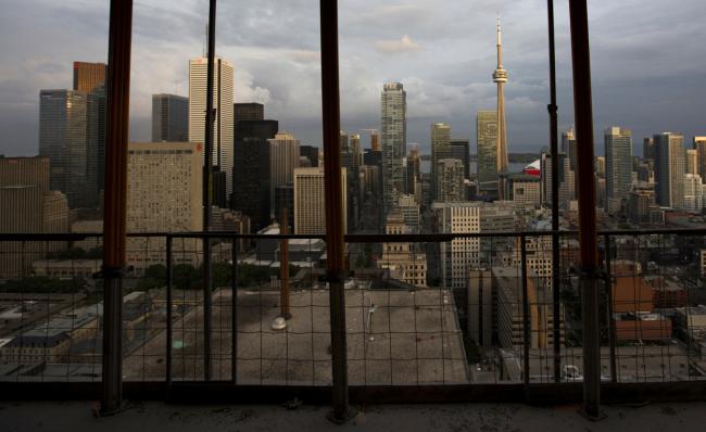 © Bloomberg. The city skyline is seen from a condominium under construction in Toronto, Ontario, Canada, on Tuesday, June 25 2013. Canadas housing agency further trimmed its forecast for housing starts this year amid modest economic and employment growth.