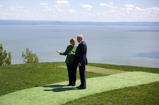 © Bloomberg. Angela Merkel, Germany's chancellor, left, speaks with U.S. President Donald Trump after standing for a family photograph during the Group of Seven (G7) Leaders Summit in La Malbaie, Quebec, Canada. Photographer: Cole Burston/Bloomberg