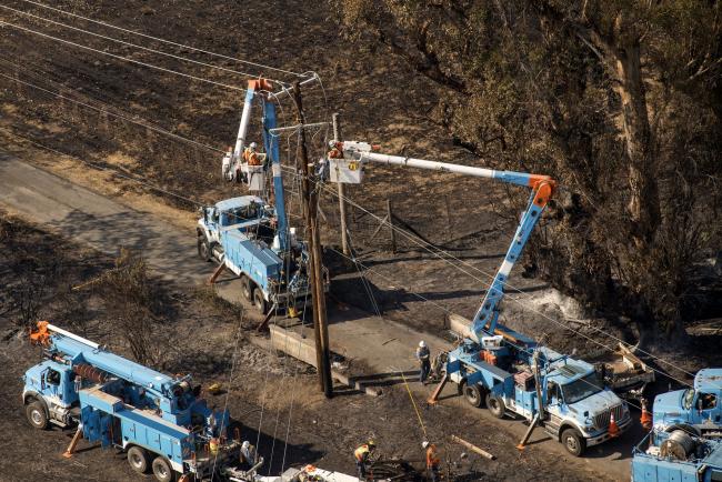 © Bloomberg. Pacific Gas & Electric Co. (PG&E) employees work to fix downed power lines burned by wildfires in this aerial photograph taken above Santa Rosa, California, U.S., on Thursday, Oct. 12, 2017.  