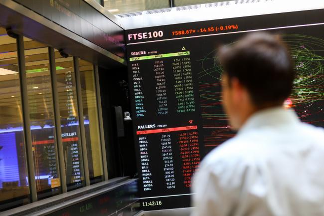 © Bloomberg. An employee looks at a screen displaying FTSE 100 share price information in the atrium of the London Stock Exchange Group Plc's offices in London, U.K., on Friday, July 6, 2018. U.K. Prime Minister Theresa May is about to unveil in more detail than ever the kind of divorce from the EU she thinks the country, Parliament and Brussels will accept, with a policy document called a 