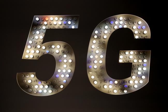 © Bloomberg. A 5G sign illuminated by light bulbs stands on the Xiaomi Corp. stand on the opening day of the MWC Barcelona in Barcelona, Spain. 