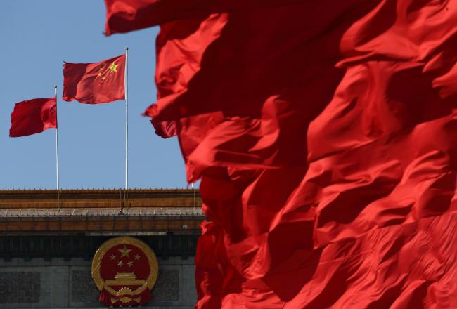 © Bloomberg. Red flags fly in front of the Chinese national flag, second left, outside the Great Hall of the People in Beijing, China,. Photographer: Tomohiro Ohsumi/Bloomberg