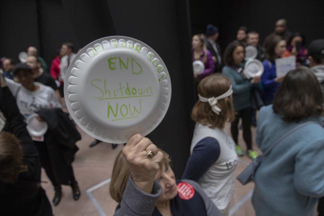 © Bloomberg. A demonstrator holds a sign on a disposable plate that reads 