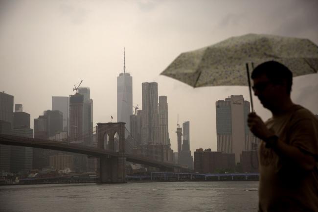 © Bloomberg. A pedestrian holding an umbrella walks through Main Street Park in the Brooklyn borough of New York, U.S., on Tuesday, May 28, 2019. Treasuries advanced, further inverting a key slice of the yield curve, while stocks fluctuated as investors positioned for what could be a protracted trade dispute with China. Photographer: Michael Nagle/Bloomberg