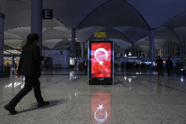 © Bloomberg. An illuminated advertising board displaying the Turkish national flag stands in the terminal during the official opening ceremony for the new Istanbul Airport in Istanbul, Turkey, on Monday, Oct. 29, 2018. President Recep Tayyip Erdogan opened one of the world’s largest airports on Monday, declaring completion of the first phase of construction a symbol of Turkey’s strength and resilience -- and a victory over forces he said are trying to sabotage its economy. Photographer: Kostas Tsironis/Bloomberg