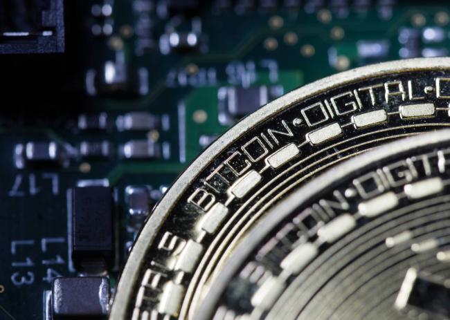 © Bloomberg. Two coins representing Bitcoin cryptocurrency sit on a computer circuit board in this arranged photograph in London, U.K., on Tuesday, Feb. 6, 2018. Cryptocurrencies tracked by Coinmarketcap.com have lost more than $500 billion of market value since early January as governments clamped down, credit-card issuers halted purchases and investors grew increasingly concerned that last year’s meteoric rise in digital assets was unjustified.