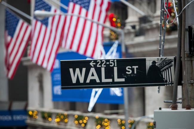 © Bloomberg. A Wall Street sign is seen in front of the New York Stock Exchange (NYSE) in New York, U.S., on Monday, Dec. 18, 2017.