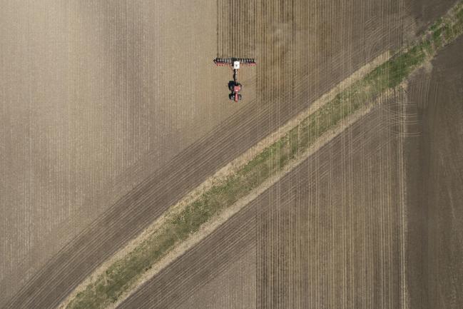 © Bloomberg. A Case IH Agricultural Equipment Inc. tractor pulls a planter through a field as corn in planted in this aerial photograph taken over a farm in Princeton, Illinois, U.S. Photographer: Daniel Acker/Bloomberg