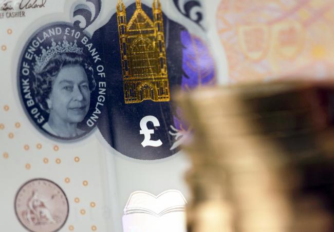 &copy Bloomberg. A transparent window featuring a portrait of Queen Elizabeth II sits next to a finely detailed metallic image of Winchester Cathedral and a colored quill on a British 10-pound banknote near a stack of one pound sterling coins in this arranged photograph in London, U.K., on Wednesday, Aug. 15, 2018. The pound's weakness is turning everyone—from students to holiday-makers—into unwitting currency traders as Brexit nears. Photographer: Chris Ratcliffe/Bloomberg