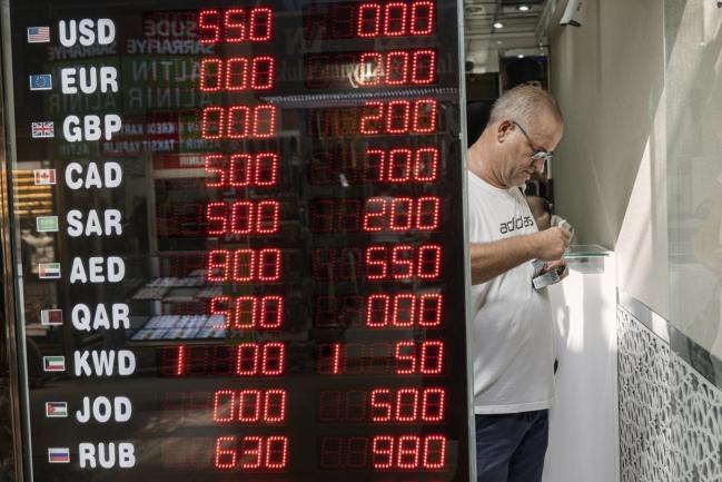 © Bloomberg. International currency exchange rates stand on display in the widow of a bureau as a worker handles Euro currency notes, in the Grand Bazaar in Istanbul, Turkey, on Friday, Aug. 10, 2018. A plunge in the lira sent tremors through global markets on Friday as tensions flared between the U.S. and Turkey, a pair of NATO allies. Photographer: Ismail Ferdous/Bloomberg