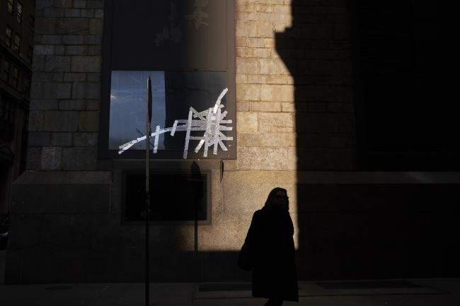 © Bloomberg. A pedestrian walks past a broken window near Wall Street in New York, U.S. Photographer: John Taggart/Bloomberg