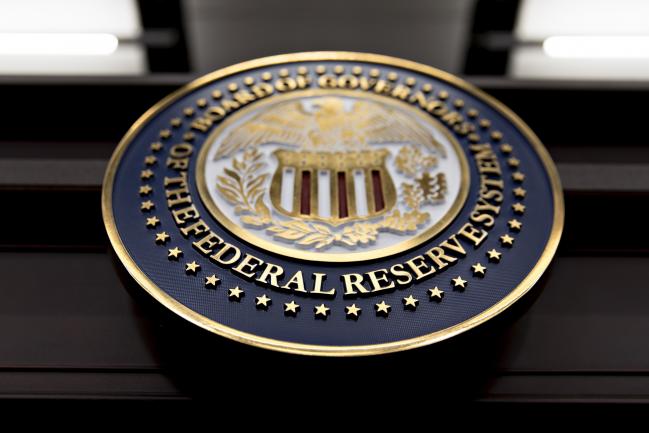 © Bloomberg. The seal of the Board of Governors of the Federal Reserve System hangs on a table before a news conference with Federal Reserve Chair Janet Yellen following a Federal Open Market Committee (FOMC) meeting in Washington, D.C., U.S., on Wednesday, Dec. 13, 2017. Federal Reserve officials followed through on an expected interest-rate increase and raised their forecast for economic growth in 2018, even as they stuck with a projection for three hikes in the coming year.