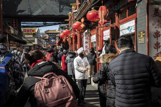 © Bloomberg. Pedestrians past food stores in Beijing, China, on Friday, Feb. 15, 2019. With a continued slowdown in industrial output and consumption, a further deceleration in China's economy will hurt demand for imported goods. Photographer: Qilai Shen/Bloomberg