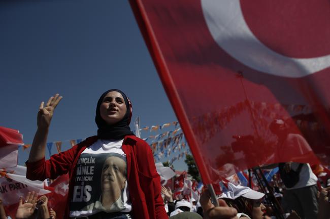 © Bloomberg. A woman wears a shirt displaying an image of Recep Tayyip Erdogan, Turkey's President, and gestures during an election campaign rally in Yalova, Turkey, on Thursday, June 14, 2018. “ 
