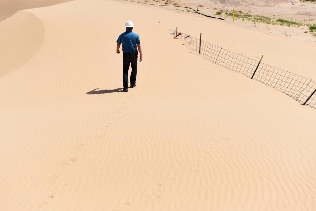 © Bloomberg. Greg Edwards walks through the sand dunes in Kermit, Texas. Photographer: Callaghan O'Hare/Bloomberg