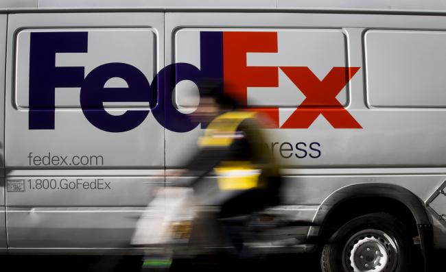 © Bloomberg. A bicyclist rides past a FedEx Corp. vehicle parked in the Midtown neighborhood of New York. 