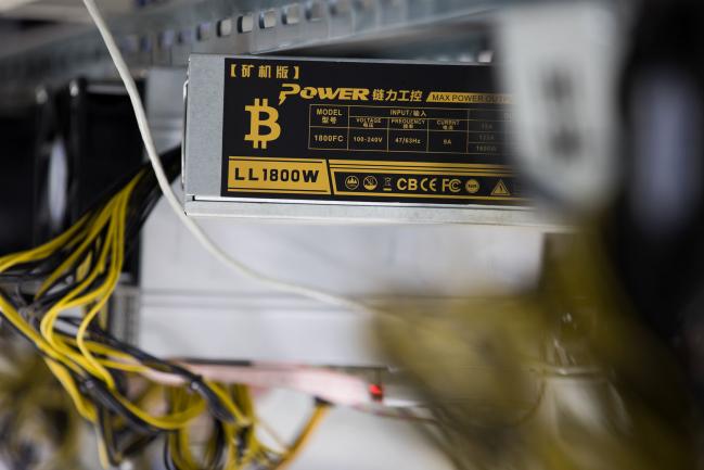 © Bloomberg. The bitcoin symbol is displayed on a power supply unit at a cryptocurrency mining facility in Incheon, South Korea, on Friday, Dec. 15, 2017. Hedge funds are pulling out of gold bets as more exciting moves in equities and cryptocurrencies make safe-haven investments look boring.