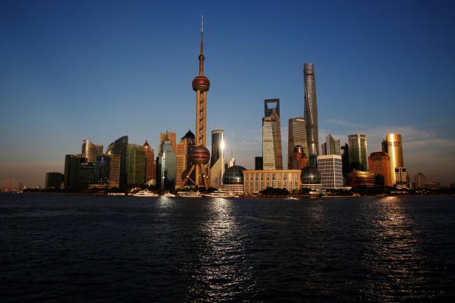 © Bloomberg. Skyscrapers and high rise towers, including the Oriental Pearl Tower, center, send reflections across the Huangpu River in Pudong, a district of Shanghai, China. Photographer: Luke MacGregor/Bloomberg