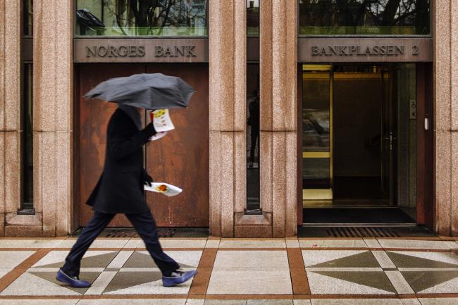 © Bloomberg. Pedestrians pass the entrance to Norway's central bank, also known as Norges Bank, in Oslo, Norway, on Thursday, Feb. 13, 2014. Norway's seasonally adjusted gross domestic product, excluding oil, gas and shipping, rose 0.6 percent in the fourth quarter, after expanding 0.5 percent in the prior three months, Oslo-based Statistics Norway said Feb. 12.