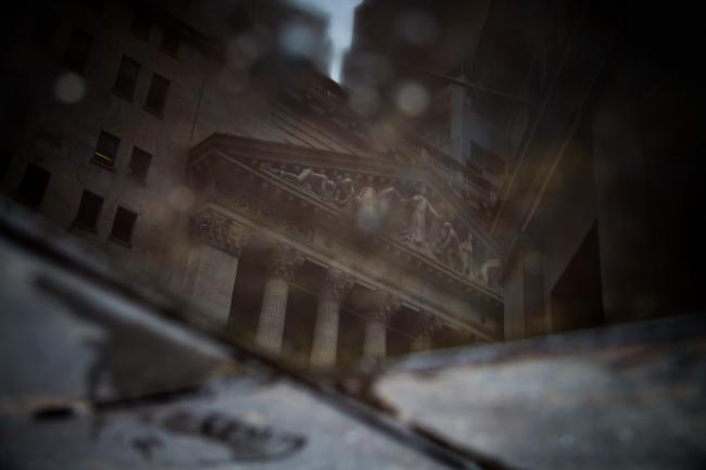 © Bloomberg. The New York Stock Exchange (NYSE) is reflected in a puddle of water on Wall Street in New York, U.S., on Monday, Oct. 30, 2017.