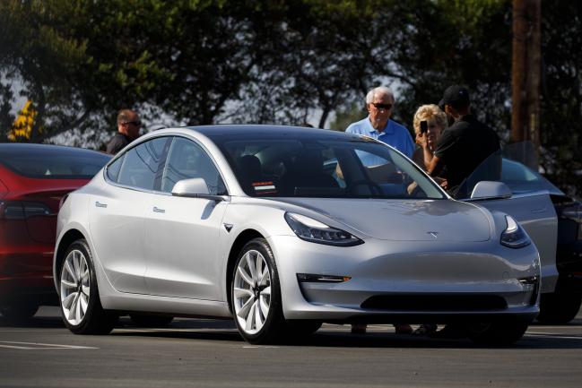 © Bloomberg. People inspect a Tesla Inc. Model 3 electric vehicle at the company's delivery center in Marina Del Rey, California, U.S., on Saturday, Sept. 29, 2018. Tesla brought the total number of Model 3 produced in the third quarter to over 51,000 vehicles. Photographer: Patrick T. Fallon/Bloomberg