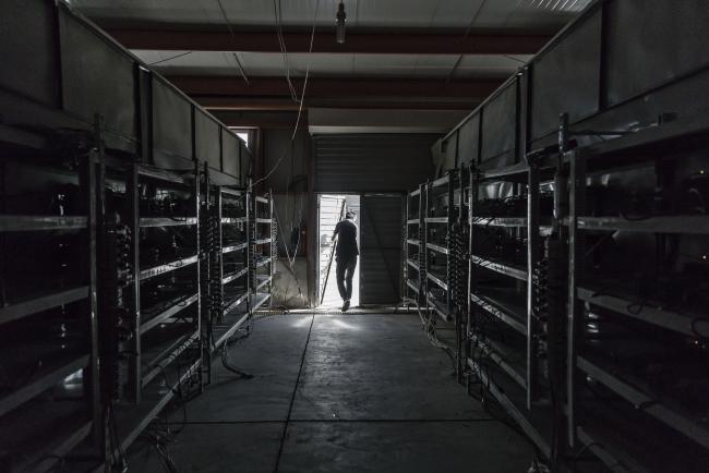 © Bloomberg. A technician exits a warehouse containing bitcoin mining machines at a mining facility operated by Bitmain Technologies Ltd. in Ordos, Inner Mongolia, China, on Friday, Aug. 11, 2017. Bitmain is one of the leading producers of bitcoin-mining equipment and also runs Antpool, a processing pool that combines individual miners from China and other countries, in addition to operating one of the largest digital currency mines in the world.