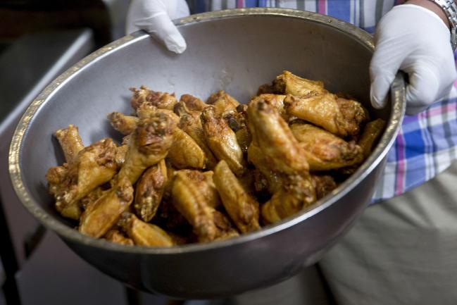 © Bloomberg. Chicken wings are removed from the fryer at the Anchor Bar in this arranged photograph in Buffalo, New York, U.S., on Wednesday, Sept. 24, 2014. The Federal Reserve Bank of New York's empire state manufacturing report for the month of September painted a picture of vibrant output, bolstered by strengthening in new orders and shipments. Photographer: Andrew Harrer/Bloomberg