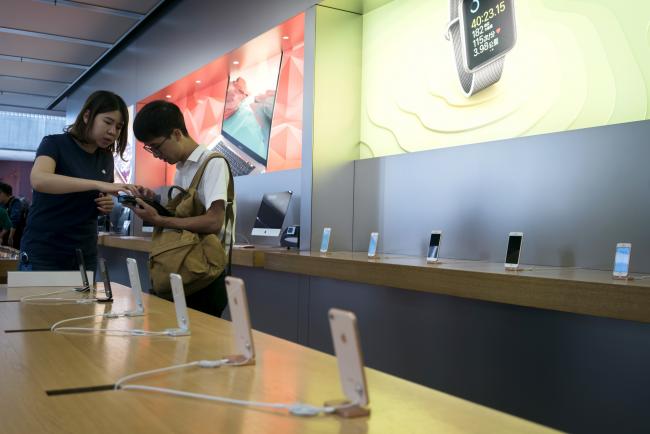 © Bloomberg. An Apple Inc. employee talks with a customer at the Apple Store at Sanlitun during the launch of the iPhone 8 in Beijing, China, on Friday, Sept. 22, 2017.  