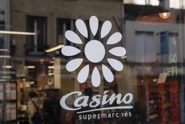 © Bloomberg. A logo sits on a window of a Casino Guichard-Perrachon SA supermarket in Paris, France, on Tuesday, Oct. 23, 2018. Hedge funds hired a lawyer to argue that French grocery magnate Jean-Charles Naouri’s stake in Casino Guichard-Perrachon SA is valued too highly on the books of his holding company, intensifying the battle between the French billionaire and short sellers. 