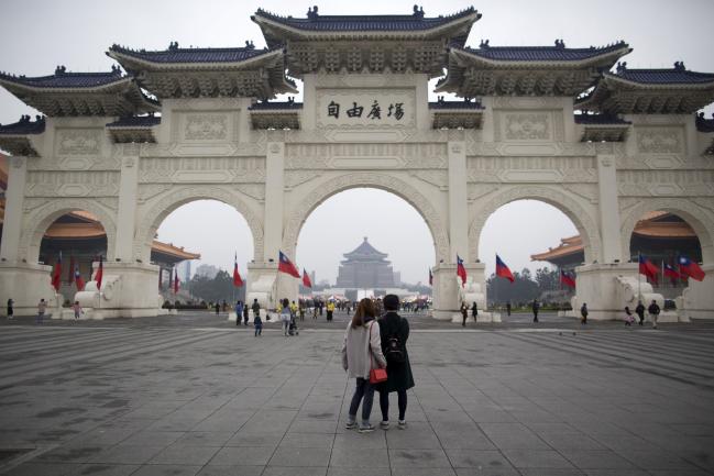 © Bloomberg. Visitors stand at Liberty Square as the Chiang Kai-shek Memorial Hall stands in the background in Taipei, Taiwan, on Sunday, Dec. 31, 2017. Taiwan’s currency rose 18 percent in 2017, its best annual performance in three decades, largely the result of a weakening greenback.