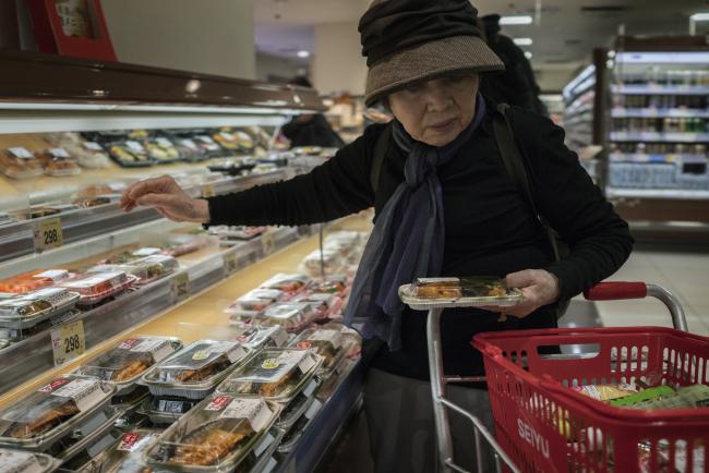 © Bloomberg. A shopper picks up a pack of cooked fish at a grocery store in the Nakano District of Tokyo, Japan, on Saturday, April 14, 2018. Japan's headline inflation measure is expected to rise to 1.1 percent this year and in 2019, from 0.5 percent in 2017, the International Monetary Fund said in its World Economic Outlook on Tuesday. Photographer: James Whitlow Delano/Bloomberg