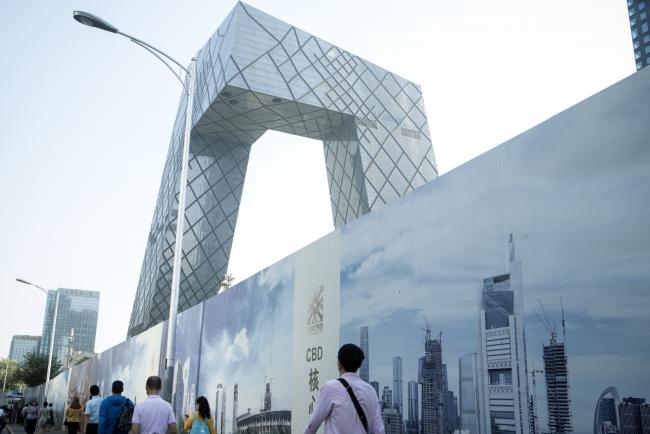 © Bloomberg. Pedestrians walk along a street near the China Central Television (CCTV) headquarters building, center, in the central business district in Beijing, China, on Friday, June 1, 2018. The People's Bank of China announced on Friday that it would add debt instruments tied to small-business and the green economy. 