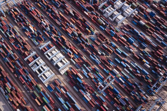 © Bloomberg. Shipping containers stand at the Qingdao Qianwan Container Terminal in this aerial photograph taken in Qingdao, China, on Monday, May 7, 2018. China's overseas shipments exceeded estimates while imports surged, as the global economy continued to support demand. 