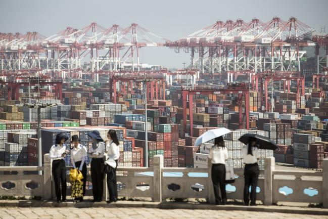 © Bloomberg. Students from the Shanghai Customs College stand at a viewing platform overlooking the Yangshan Deep Water Port in Shanghai, China, on Tuesday, July 10, 2018. China told companies to boost imports of goods from soybeans to seafood and automobiles from countries other than the U.S. after trade tensions between the world's two biggest economies escalated into a tariff war last week. 