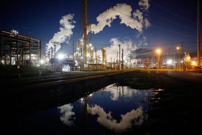 © Bloomberg. Emissions from an oil refinery are reflected in a street puddle at dusk in Texas City, Texas, U.S., on Thursday, Feb. 16, 2017. Asia's energy importers will benefit from more opportunities for arbitrage, supply diversification if U.S. President Donald Trump's pro-energy policies drive meaningful upsurge in U.S. crude, LNG exports, BMI Research reports.