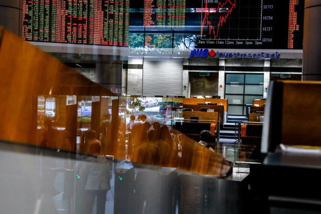 © Bloomberg. People are reflected on a glass door as monitors display stock prices inside the trading gallery of the RHB Investment Bank Bhd. headquarters in Kuala Lumpur, Malaysia, on Monday, May 14, 2018. Malaysia's markets showed few signs of investor panic as trading reopened after Mahathir Mohamad swept to power in a surprise election outcome. Photographer: Sanjit Das/Bloomberg