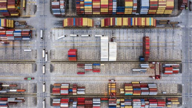 © Bloomberg. Shipping containers sit stacked at the Yangshan Deepwater Port, operated by Shanghai International Port Group Co. (SIPG), in this aerial photograph taken in Shanghai, China, on Friday, May 10, 2019. The U.S. hiked tariffs on more than $200 billion in goods from China on Friday in the most dramatic step yet of President Donald Trump's push to extract trade concessions, deepening a conflict that has roiled financial markets and cast a shadow over the global economy. 