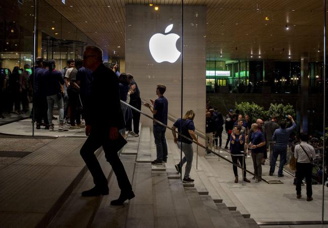 © Bloomberg. An Apple logo is illuminated as customers walk through the new Apple Inc. Michigan Avenue store during the store\\'s opening in Chicago.