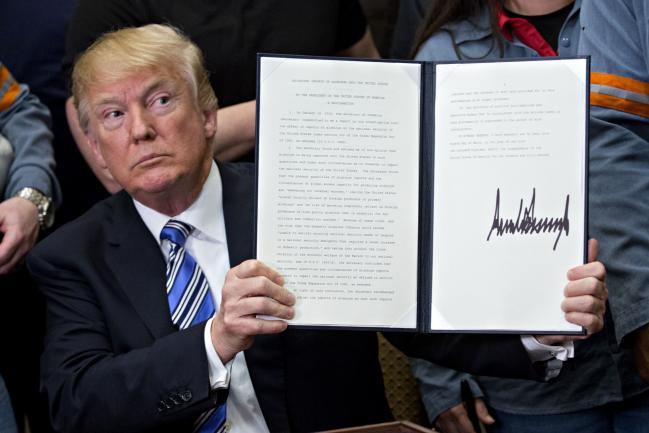 © Bloomberg. Trump holds a signed proclamation on adjusting imports of aluminum into the United States on March 8.