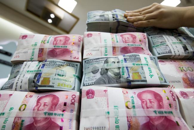 © Bloomberg. An employee arranges genuine bundles of U.S. one-hundred dollar banknotes and Chinese one-hundred yuan in an arranged photograph at the Counterfeit Notes Response Center of KEB Hana Bank in Seoul, South Korea, on Monday, Aug. 14, 2017. China's factory output and investment slowed somewhat in July, according to data released today, yet the yuan appeared not to take the data as negative, if in fact it's paying attention to it at all. Photographer: SeongJoon Cho/Bloomberg