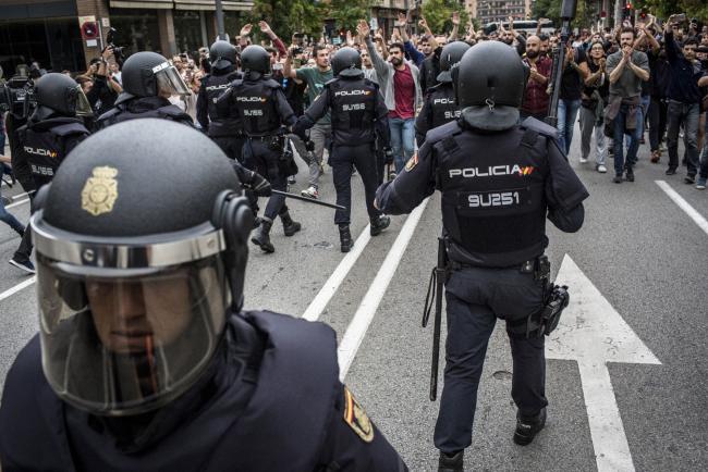 © Bloomberg. Police officers confront pro Catalan referendum supporters in Sabadell, Spain on Oct. 1.