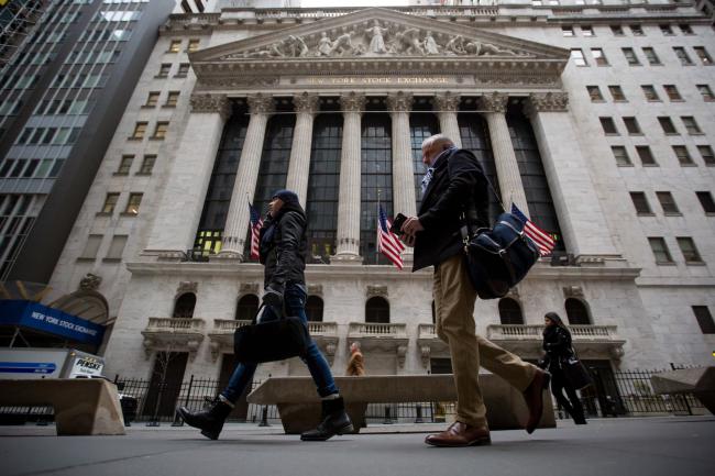© Bloomberg. Pedestrians pass in front of the New York Stock Exchange (NYSE) in New York, U.S., on Tuesday, Feb. 6, 2018. U.S. equity indexes climbed higher after a rocky start, and the benchmark gauge for U.S. share volatility reversed course after hitting a two-year high.