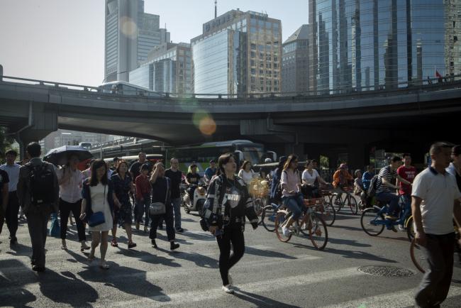 © Bloomberg. Pedestrians cross a road next to cyclists and other vehicles in the central business district in Beijing, China, on Friday, June 1, 2018. The People's Bank of China announced on Friday that it would add debt instruments tied to small-business and the green economy. 