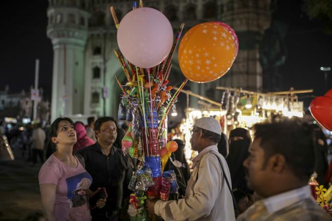 © Bloomberg. Customers look at a vendor's balloons and toys near Charminar monument and mosque in Hyderabad, India, on Friday, March 15, 2019. The success of India's $5 billion swap auction on March 26 will decide whether it will become a popular instrument in the central bank's liquidity tool box. The move will bulk up the central bank's foreign-exchange reserves while injecting cash into the banking system to ease the liquidity crunch typically seen before the fiscal year-end in March. 