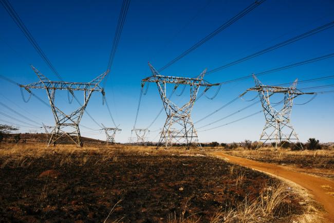 © Bloomberg. Electrical power lines hang from transmission pylons in the Tembisa township outside Johannesburg, South Africa, on Tuesday, July 17, 2018. 