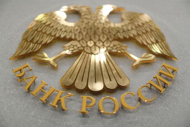 © Bloomberg. The crest of the Russian Federation sits on display at the headquarters of Bank Rossii, ahead of a news conference to announce interest rates in Moscow, Russia, on Friday, June 16, 2017. Russia's central bank slowed its pace of monetary easing with the third cut in borrowing costs this year as policy makers shift the focus to keeping inflation near their target. Photographer: Andrey Rudakov/Bloomberg