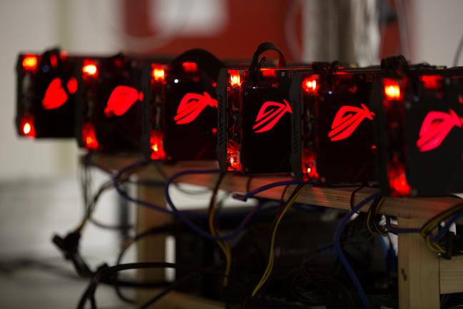 © Bloomberg. Red lights illuminate cryptocurrency mining rig units at the SberBit mining 'hotel' in Moscow, Russia.