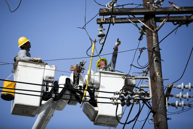 © Bloomberg. Puerto Rico Electric Power Authority (PREPA) employees fix power lines in Santurce, San Juan, Puerto Rico, on Thursday, Oct. 19, 2017.