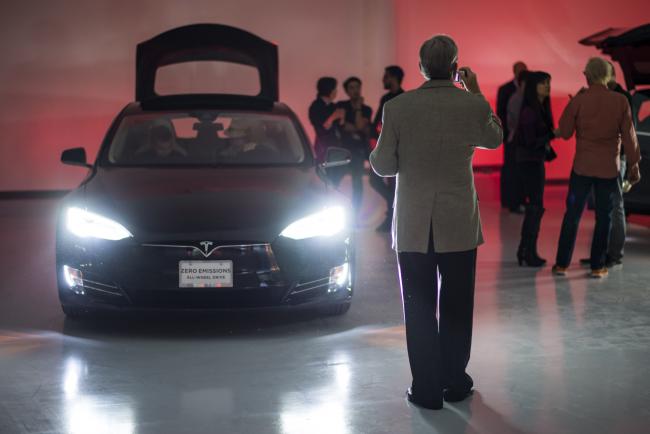 © Bloomberg. A guest stands in front of a Tesla Motors Inc. Model S electric vehicle on display at the company's new showroom in San Francisco, California, U.S. Photographer: David Paul Morris/Bloomberg
